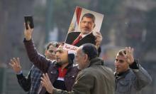 Supporters of the Muslim Brotherhood and ousted Egyptian President Mohamed Mursi hold a copy of the Koran and Mursi's picture at Talaat Harb Square, in Cairo, January 25, 2015. PHOTO BY REUTERS/Mohamed Abd El Ghany