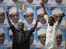 Supporters of presidential candidate Muhammadu Buhari gesture in front of his election posters in Kano, March 27, 2015. PHOTO BY REUTERS/Goran Tomasevic