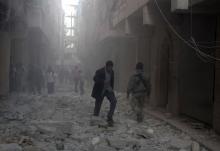 People walk on rubble at a damaged site after what activists said was an air raid by forces loyal to Syrian President Bashar Al-Assad, in Aleppo's al-Saliheen district