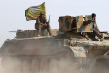 Syrian Democratic Forces fighters sit on a vehicle in the north of Raqqa city, Syria. PHOTO BY REUTERS/Rodi Said