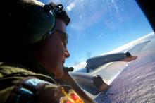 Seargent Trent Wyatt looks out an observation window aboard a Royal New Zealand Air Force (RNZAF) P3 Orion maritime search aircraft as it flies over the southern Indian Ocean looking for debris from missing Malaysian Airlines flight MH370