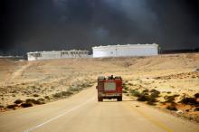 A truck drives as smokes rises following a fire in an oil storage tank at the port of Es Sider, in Ras Lanuf, Libya, January 23, 2016. PHOTO BY REUTERS/Stringer