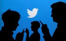 People holding mobile phones are silhouetted against a backdrop projected with the Twitter logo in this illustration picture taken September 27, 2013. REUTERS/Kacper Pempel/Illustration