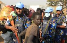 A displaced boy walks past U.N. police from Bangladesh who are on patrol at Tomping camp in Juba, where some 15,000 displaced people who fled their homes are sheltered by the United Nations