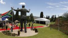 People stand near the 9-metre (30-feet) bronze statue of the late former South African President Nelson Mandela as it is unveiled as part of the Day of Reconciliation Celebrations at the Union Buildings in Pretoria
