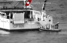 Italian coast guard officers stand on a dinghy beside an Italian coast guard vessel as a massive search and rescue operation is conducted at sea after a boat carrying migrants capsized overnight, in this still image taken from video April 19, 2015. PHOTO BY REUTERS