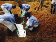 Volunteers lower a corpse, which is prepared with safe burial practices to ensure it does not pose a health risk to others and stop the chain of person-to-person transmission of Ebola, into a grave in Kailahun, August 2, 2014. PHOTO BY REUTERS/WHO/Tarik Jasarevic