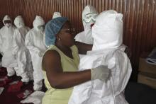 A World Health Organization (WHO) health worker gives a demonstration on how to put on a protective suit to health worker trainees in Freetown, Sierra Leone