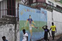 Men walk by a mural that reads "Get the hell of Liberia, Ebola! And don't come back" in Monrovia, Liberia, April 1, 2016. PHOTO BY REUTERS/James Giahyue