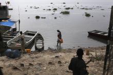 A woman gets water next to two men from the anti-government forces heading towards the Nile River in the town of Malakal, Upper Nile State, which is currently held by anti-government forces