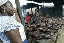 A woman stands by a table table selling smoked bush meat at a specialist market in the Yopougon area of Abidjan in a file day.