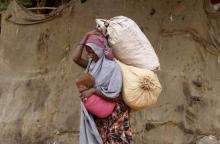 A displaced Somali woman carries a child and her belongings as she arrives at a temporary dwelling after fleeing famine in the Marka Lower Shebbele regions to the capital Mogadishu, September 20, 2014. PHOTO BY REUTERS/Feisal Omar