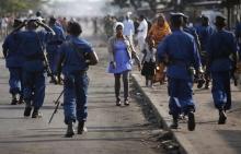 A woman passes by policemen during a protest against Burundi President Pierre Nkurunziza and his bid for a third term in Bujumbura, Burundi, June 2, 2015. PHOTO BY REUTERS/Goran Tomasevic