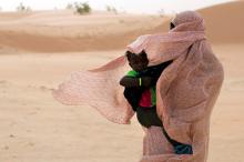  A woman shields her child from the wind while walking on sand dunes in Nouakchott, June 22, 2014. PHOTO BY REUTERS/Joe Penney