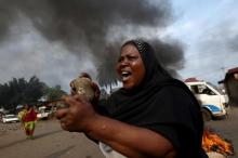 A woman gestures with stones during a protest against President Pierre Nkurunziza and his bid for a third term in Bujumbura, Burundi, May 26, 2015. PHOTO BY REUTERS/Goran Tomasevic