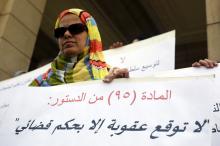 A woman carries a sign that reads "Don't penalise without judicial rule" during a protest by faculty members about the ban on partisan political activity on campus, at Cairo University in Cairo, October 13, 2014. PHOTO BY REUTERS/Amr Abdallah Dalsh