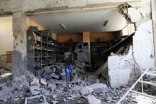 A worker inspects the damage inside the Faculty of Mechanical Engineering Technology school compound after a Libyan air force plane dropped a bomb on it in Benghazi