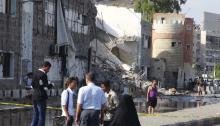 People gather at the scene of a car bomb attack on a police compound in the southern Yemeni city of Aden