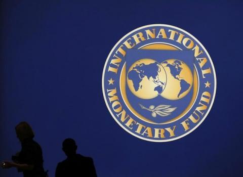 Visitors are silhouetted against the logo of the International Monetary Fund at the main venue for the IMF and World Bank annual meeting in Tokyo, October 10, 2012. PHOTO BY REUTERS/Kim Kyung-Hoon