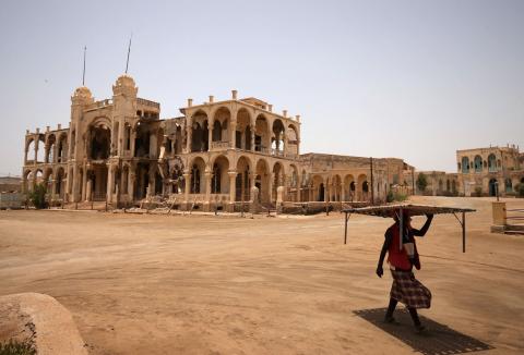 A man carries a table as he walks past the ruins of a building in the port city of Massawa, Eritrea, July 22, 2018. PHOTO BY REUTERS/Tiksa Negeri