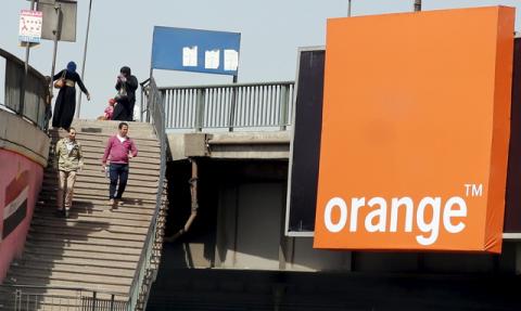 People walk past a sign of French telecom operator Orange hanging from a bridge in Cairo, Egypt, March 13, 2016. PHOTO BY REUTERS/Amr Abdallah Dalsh