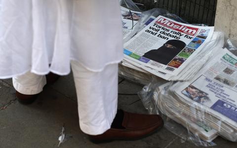 A man looks at newspapers outside the Brick Lane Jamme Masjid (mosque) before Friday prayers in east London