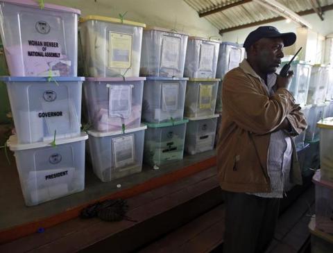 A plain clothed policeman stands in front of ballot boxes in a tallying centre at Mathare slum in Nairobi