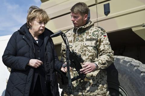German Chancellor Angela Merkel looks at a Heckler & Koch MP7 submachine gun during a visit to the German army's Camp Marmal in Mazar-e-Sharif