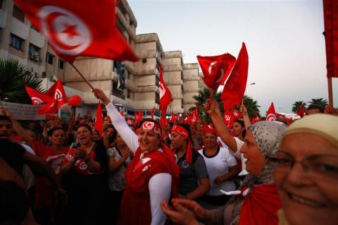 Anti-government protesters wave Tunisian national flags and shout slogans during a demonstration in Tunis