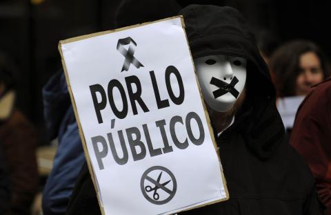 A protestor wears a mask with black tape over the mouth during a demonstration against government austerity measures and the passing of a new law by the cabinet which toughens penalties on protesters