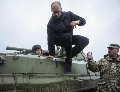 Ukrainian Prime Minister Arseny Yatseniuk jumps off an armored personnel carrier (APC) during a visit to the International Center of Peacekeeping and Security in Yavoriv, west of Lviv, October 21, 2014. PHOTO BY REUTERS/Andrew Kravchenko