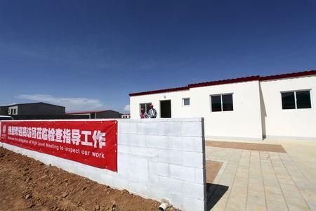 Chinese workers stand behind banners at a construction site in Lubango, Angola, March 5, 2014. PHOTO BY REUTERS/Herculano Coroado