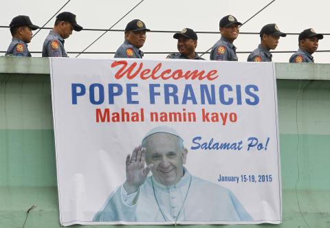 Members of the Philippine National Police walk past a banner with an image of Pope Francis as they go to their designated area in Manila, January 15, 2015. PHOTO BY REUTERS/ Cheryl Ravelo