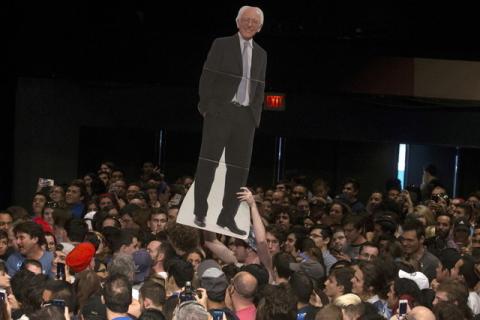 A man walks though a crowd of supporters with a cut-out depicting Bernie Sanders before a campaign event in Miami, March 8, 2016. PHOTO BY REUTERS/Carlo Allegri
