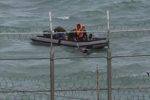 Moroccan soldiers on a boat attempt to board a would be migrant on Moroccan waters near the border fence that separates Spain's North African enclave of Ceuta from neighboring Morocco, March 2, 2014. PHOTO BY REUTERS/Juan Medina