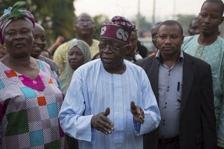 Former governor of Lagos state Bola Ahmed Tinubu (C) speaks to electoral officials before voting in governorship elections in Lagos, Nigeria, April 11, 2015. PHOTO BY REUTERS/Joe Penney