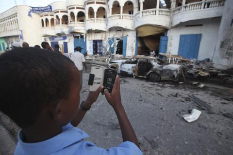 A boy takes pictures at the scene of a Sunday night explosion outside the Oromo restaurant in Mogadishu