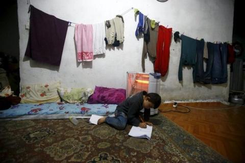 A Syrian refugee boy writes on the floor as his mother takes part in an interview with Reuters in Istanbul, Turkey, December 16, 2015. PHOTO BY REUTERS/Osman Orsal