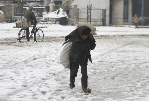 A boy carries firewood as he makes his way through snow in the Duma neighbourhood of Damascus, January 7, 2015. PHOTO BY REUTERS/Badra Mamet