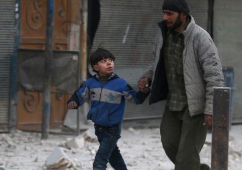 A man holds the hand of a boy as they flee deeper into the remaining rebel-held areas of Aleppo, Syria, December 9, 2016. PHOTO BY REUTERS/Abdalrhman Ismail
