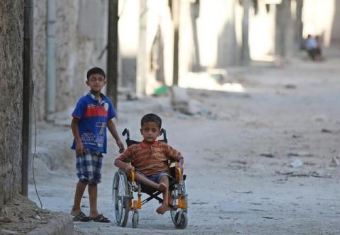 Boys, one of them in a wheelchair, go down a street in the rebel-held al-Sheikh Said neighbourhood of Aleppo, Syria, September 1, 2016. PHOTO BY REUTERS/Abdalrhman Ismail