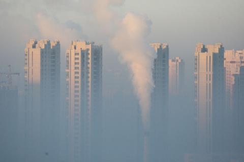 A chimney is seen in front of residential buildings during a polluted day in Harbin, Heilongjiang Province, China, January 21, 2016. PHOTO BY REUTERS/Stringer