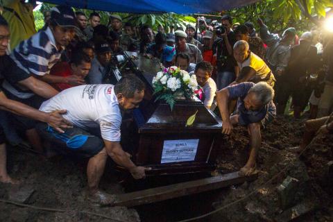 Relatives lower the coffin containing the body of Hayati Lutfiah, a passenger of AirAsia QZ8501, during her burial at a cemetery in Surabaya, January 1, 2015. PHOTO BY REUTERS/Sigit Pamungkas