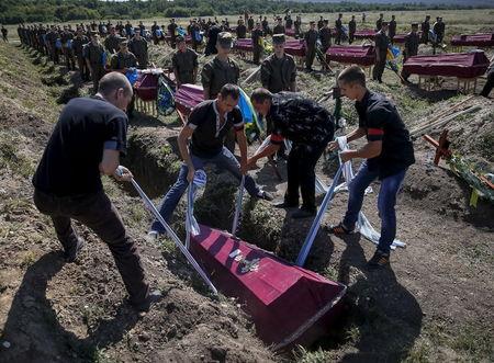 Workers take part in a mass funeral ceremony to bury 57 unidentified members of Ukrainian military forces who were killed in the conflict in eastern regions, in the settlement of Kushuhum near Zaporizhia, Ukraine, August 7, 2015. PHOTO BY REUTERS/Gleb Garanich