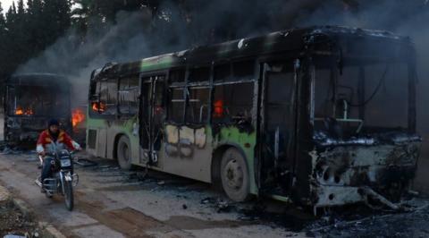 A man on a motorcycle drives past burning buses while en route to evacuate ill and injured people from the besieged Syrian villages of al-Foua and Kefraya, after they were attacked and burned, in Idlib province, Syria, December 18, 2016. PHOTO BY REUTERS/Ammar Abdullah