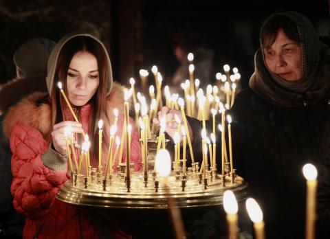 People light candles during a religious service at a church in Kiev