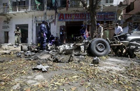 Somali soldiers and explosion experts assess the wreckage of a car destroyed in a bomb explosion at a local government headquarters that killed five people in Somalia's capital Mogadishu, April 11, 2016. PHOTO BY REUTERS/Ismail Taxta