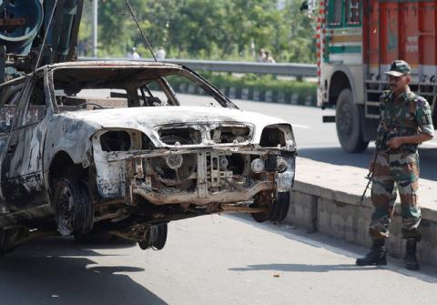 A soldier looks at a burnt out car after a day of violence in Panchkula, India, August 26, 2017. PHOTO BY REUTERS/Cathal McNaughton