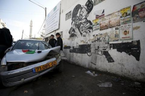 Palestinians gather around a damaged car which Israeli army said was used by Palestinians in an attempt to ram Israeli security forces during an arrest raid in the Qalandia refugee camp, near the West Bank city of Ramallah, December 16, 2015. PHOTO BY REUTERS/Mohamad Torokman
