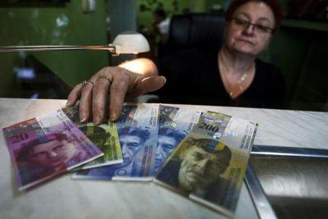 A cashier displays Swiss bank notes at a currency exchange office in Warsaw, January 16, 2015. PHOTO BY REUTERS/Adam Stepien